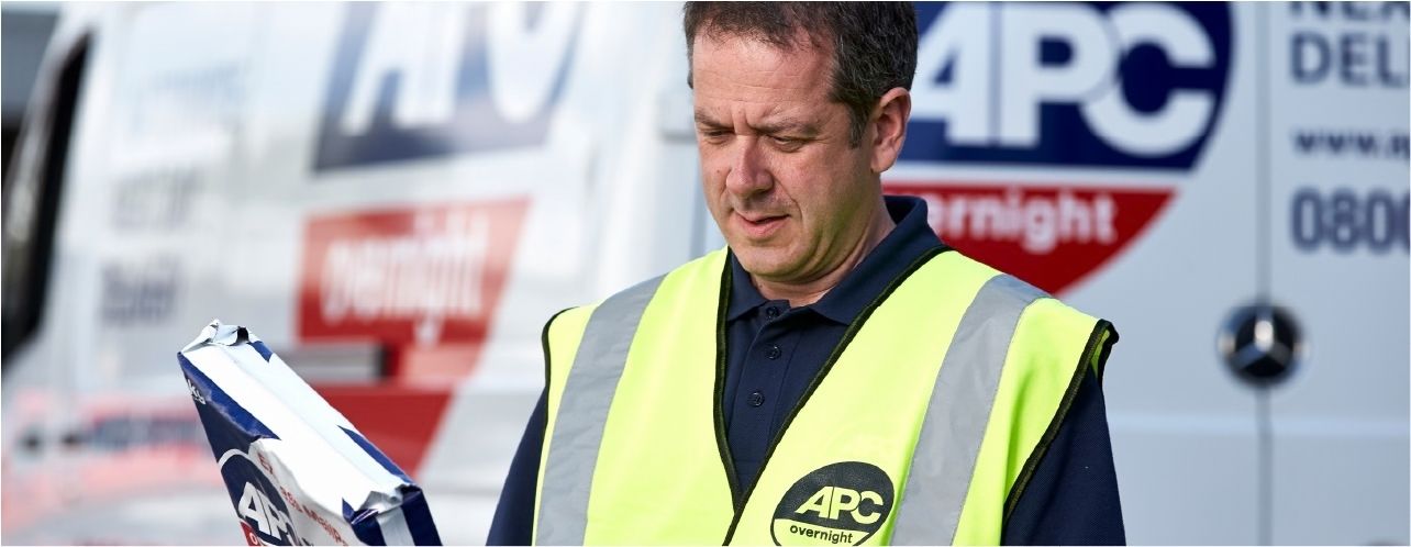 APC courier handling a customer parcel beside a delivery van